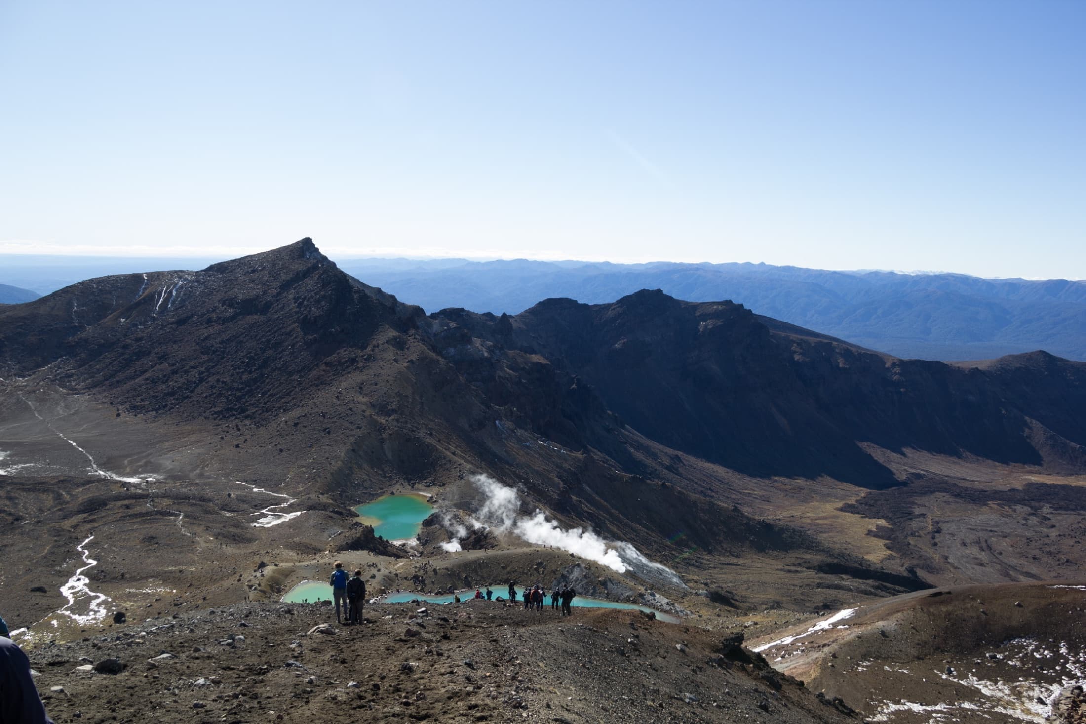 The Emerald Lakes and steaming vents seen from the ridge, hikers on the path below