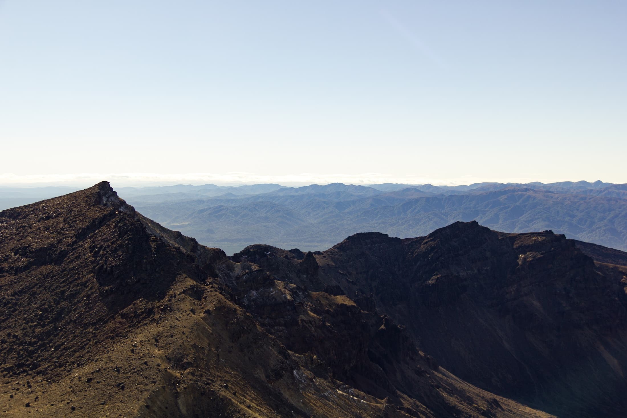Layered volcanic ridgelines receding into the distance under a pale sky